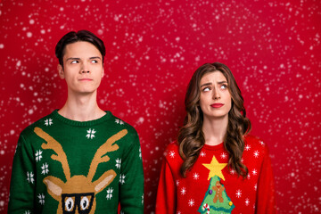 Photo of young family wife husband wear ugly sweaters suspiciously look empty space make choice decision isolated on red color background