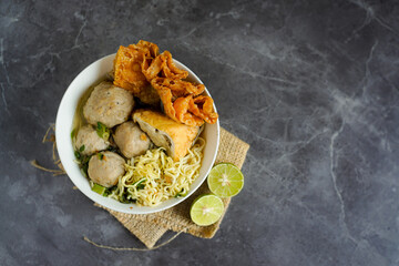 A bowl of Bakso Malang, a popular Indonesian dish featuring meatballs, noodles, and fried tofu served in a savory broth.