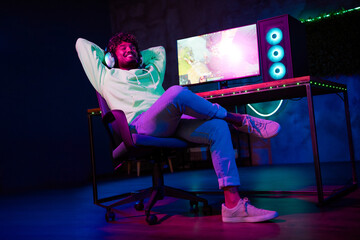 Full size photo of gamer nice young male relax winner play computer strategy game late night room indoors purple blue neon light © deagreez