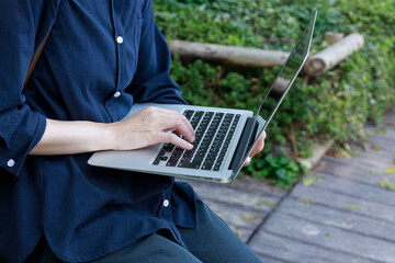 公園でノートパソコンを使用している女性　屋外　仕事　イメージ