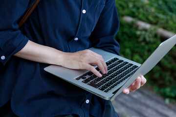 公園でノートパソコンを使用している女性　屋外　仕事　イメージ