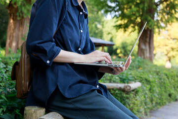 公園でノートパソコンを使用している女性　屋外　仕事　イメージ