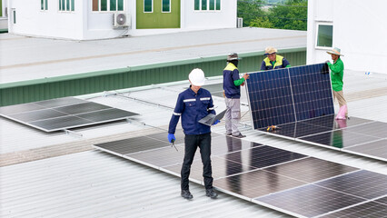 A team of technicians inspects solar panels on metal rooftop, equipped with tools, laptops, and...