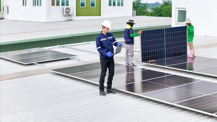 A team of technicians inspects solar panels on metal rooftop, equipped with tools, laptops, and...