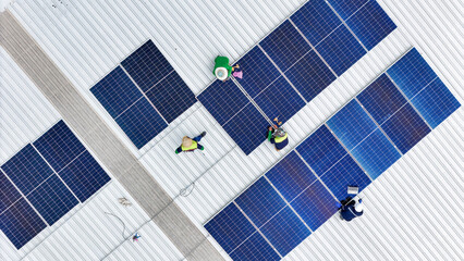 A team of technicians inspects solar panels on metal rooftop, equipped with tools, laptops, and safety gear. A scene highlights teamwork in renewable energy maintenance and sustainable infrastructure. © ultramansk