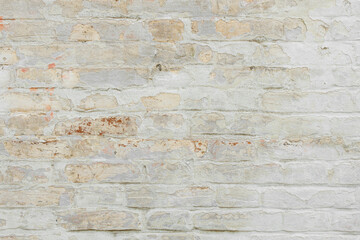 Beige grungy brick wall. Free space for an inscription. Can be used as a background or poster. Fragment of a wall with bumps and shabby plaster.