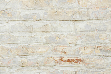 Fototapeta premium Beige grungy brick wall. Free space for an inscription. Can be used as a background or poster. Fragment of a wall with bumps and shabby plaster.