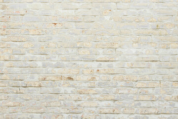 Beige grungy brick wall. Free space for an inscription. Can be used as a background or poster. Fragment of a wall with bumps and shabby plaster.