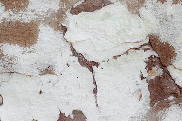 White texture of a concrete wall with natural relief and damage in the form of chips and scratches. Fragment of an old stone surface with a crack. Dark rough surface with a place for an inscription