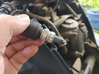 The motorcycle repairman is checking the spark plugs on an automatic motorcycle engine.