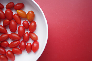 Assorted Cherry Tomatoes arranged on a white plate, with a vibrant red background