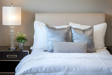A cozy bedroom featuring a neatly made bed with decorative pillows and a bedside lamp.