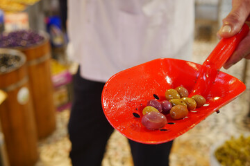 A Variety of Colorful Olives Being Expertly Served in a Bright Red Scoop Dish Today