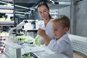Young boy immersed in a lab experiment with wide-eyed wonder. His excitement and curiosity reflect...