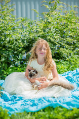 A girl is holding a beautiful cat in her arms. A child and a pet, a pet.