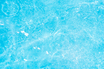 Blue water with ripples on the surface. Defocus blurred transparent blue colored clear calm water surface texture with splashes and bubbles. Water waves with shining pattern texture background.