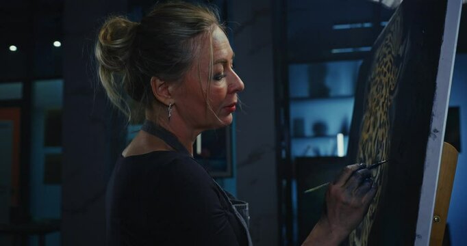 Woman Painting Leopard Portrait in Dark Studio