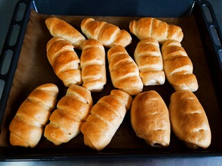 Fresh hot bread rolls. Sausages in dough. Rolled Sausage breads on a baking tray.