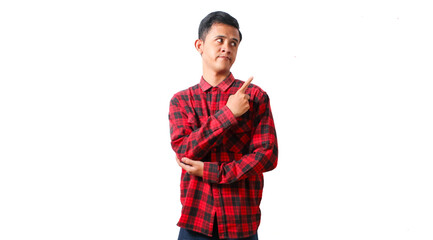 Asian man wearing red checkered casual shirt pointing to the side of empty space with curious expression. Isolated white background.