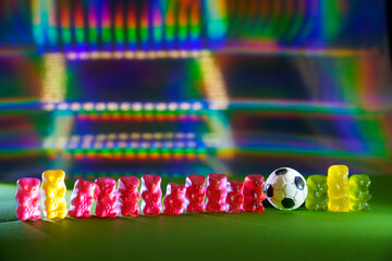 Gummy bear (German: Gummibär) scene: set up as a football team in the stadium under floodlights....