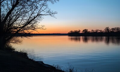 lake reflecting the colors of an evening sky, with silhouettes of trees in the background