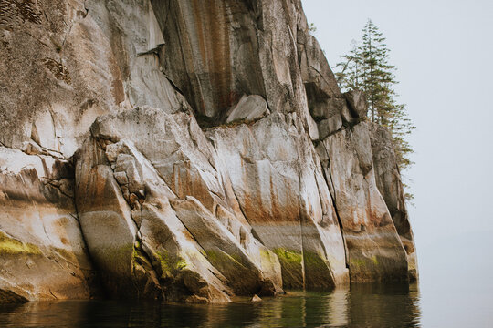 A stunning cliffside adorned with lush greenery, towering over calm ocean. The serene landscape captures the essence of nature's beauty and tranquility, highlighting the majesty of the rock formation