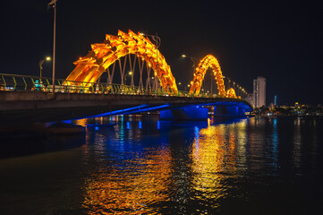 Dragon Bridge over the Han River is a famous landmark in Da Nang in Vietnam at night with a golden illuminated