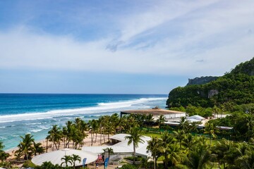 Naklejka premium Scenic Coastal View with Lush Greenery and Ocean Waves Crashing onto the Shore, Guam