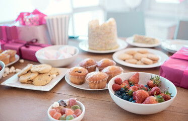 Sweet, treats and table for party at house with birthday celebration, luxury dessert and healthy fruit. Food, cupcake and surprise breakfast with present, sugar cookies and nutrition snack in lounge