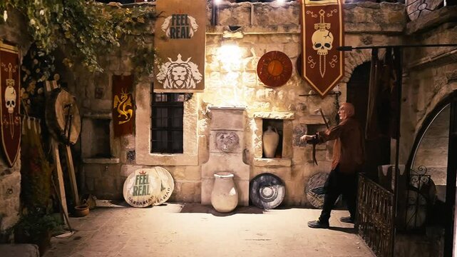 Axe throwing by bald man inside a medieval courtyard, throwing a sharp axe, pagan viking style