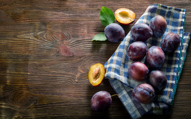 fresh plums on a kitchen towel on a wooden table, AI generated