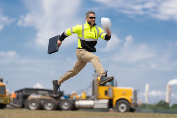Supervisor jumping. Excited builder construction worker jumping at trucks. Man engineer running to...