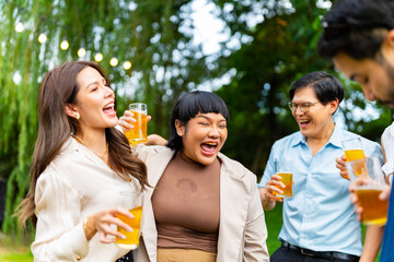 Group of Happy Asian millennial generation people friends enjoy and fun toasting beer glasses celebration reunion meeting at outdoor dinner party in the garden at restaurant on holiday vacation.