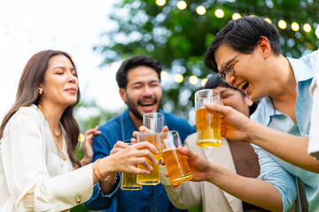 Group of Happy Asian millennial generation people friends enjoy and fun toasting beer glasses celebration reunion meeting at outdoor dinner party in the garden at restaurant on holiday vacation.