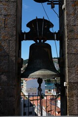 Obraz premium Bronze bell in a stone tower with town view.