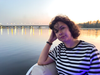 Fototapeta premium A woman is sitting on a boat in the water, looking at the camera