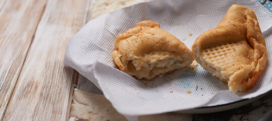 Close-up of an elderly woman's hands preparing cheese-filled panzerotto in a rustic pan, highlighting traditional cooking techniques.