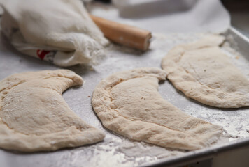 Close-up of an elderly woman's hands preparing cheese-filled panzerotto in a rustic pan, highlighting traditional cooking techniques.