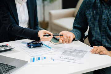 Business professionals finalize a car sale agreement with paperwork and model car, capturing themes