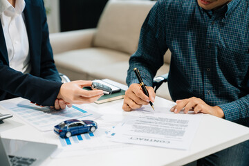 Business professionals finalize a car sale agreement with paperwork and model car, capturing themes