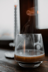 coffee in glass cup with burning candle on wooden table