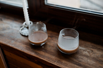 coffee in glass cup with burning candle on wooden table