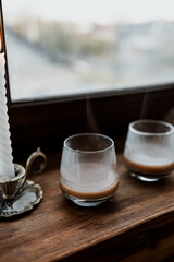 coffee in glass cup with burning candle on wooden table