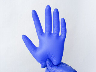 Inflated blue, medical glove in doctor's hand on white background. International Day of dentist. International Doctor's Day.