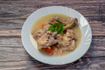Boiled chicken thighs with potatoes and carrots in a white plate. Boiled chicken meat.
