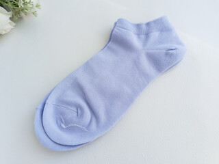 A new pair of blue socks lies on a white table. Thin, short socks. Advertising background, space for text.