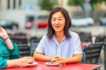 Asian woman drinking coffee with disabled friend