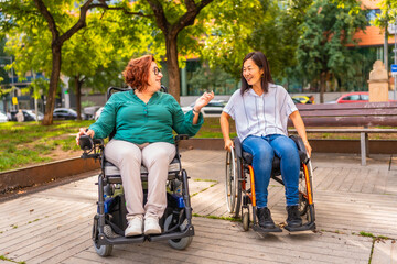 Two friends in wheelchairs chatting in the public park