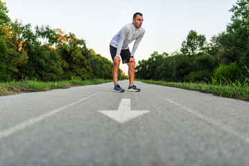 Tired male runner taking a break during training outside in the park