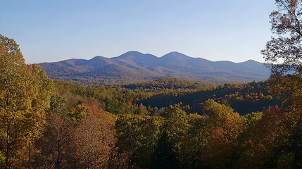 Fototapeta premium Panoramic view of a mountainous landscape with fall foliage in the foreground.